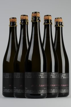 Ein Foto mit fünf Flaschen Hattenheimer Heiligenberg Lieu-Dit Riesling Sekt Brut des Jahrgangs 2021 von W. E. Frank, die in V-Form angeordnet sind.